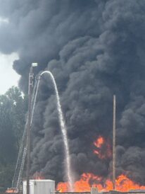 Firefighters spray water onto a fire burning near railroad tracks west of the Grain Craft facility on 30th Street on Tuesday, Aug. 26, 2025.
